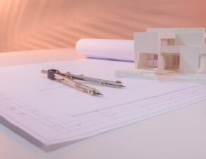 A fresh blueprint or architectural floor plan rolled out flat on a clean surface, with a small miniature building model, a compass, and a pen nearby. How to start a business in Florida
